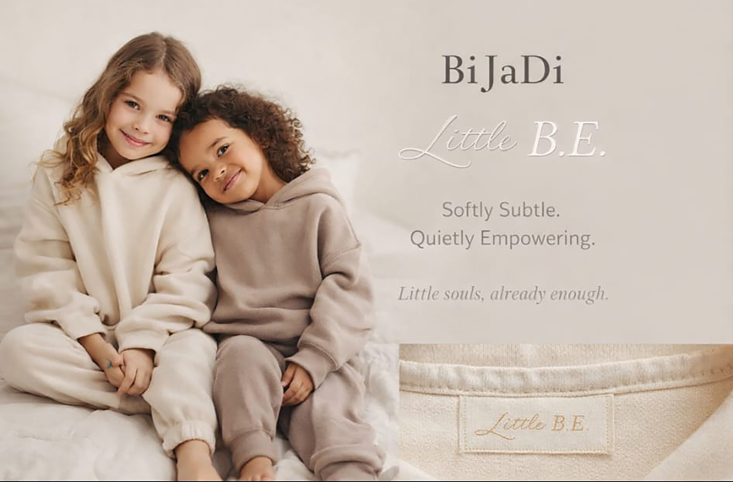 Two children in Little B.E. hoodies — cream and taupe — sitting together